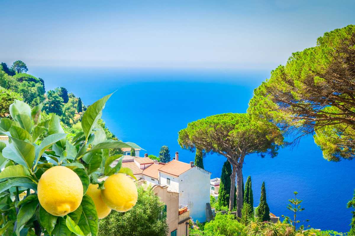 Escursionisti con zaini in cammino su un sentiero panoramico tra la vegetazione mediterranea di Capri, Faraglioni sullo sfondo